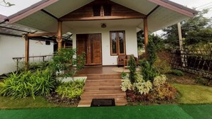 Een modern huis met een overdekte veranda, een houten trap en een verzorgde tuin.