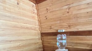 Una cocina pequeña con paneles de madera, un lavamanos, un dispensador de agua y una mesita.