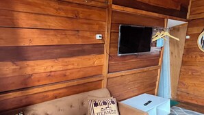 Un interior de madera con un sofá, una mesita y un televisor montado en la pared.