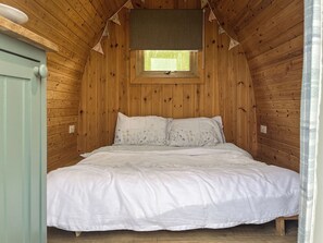 A wooden-paneled bedroom with a bed, a window, and a ceiling fan.
