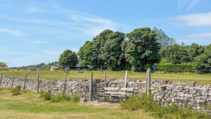 A rural landscape with a stone wall, a wooden bench, and a swing set. - Wensleydale Retreat - UK50456 (Leyburn)
