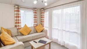 A living room with a sofa, two yellow pillows, a wooden coffee table, and a remote control. - Wensleydale Retreat - UK50456 (Leyburn)