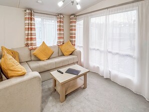 Ein Wohnzimmer mit einer Couch, zwei gelben Kissen, einem Holztisch und einer Fernbedienung.