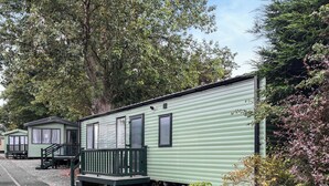 A row of green mobile homes with a small porch and a window. - Wensleydale Retreat - UK50456 (Leyburn)
