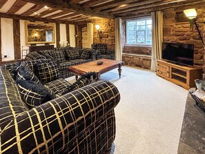 Un salon chaleureux avec un grand canapé, une table basse en bois et une cheminée en pierre.