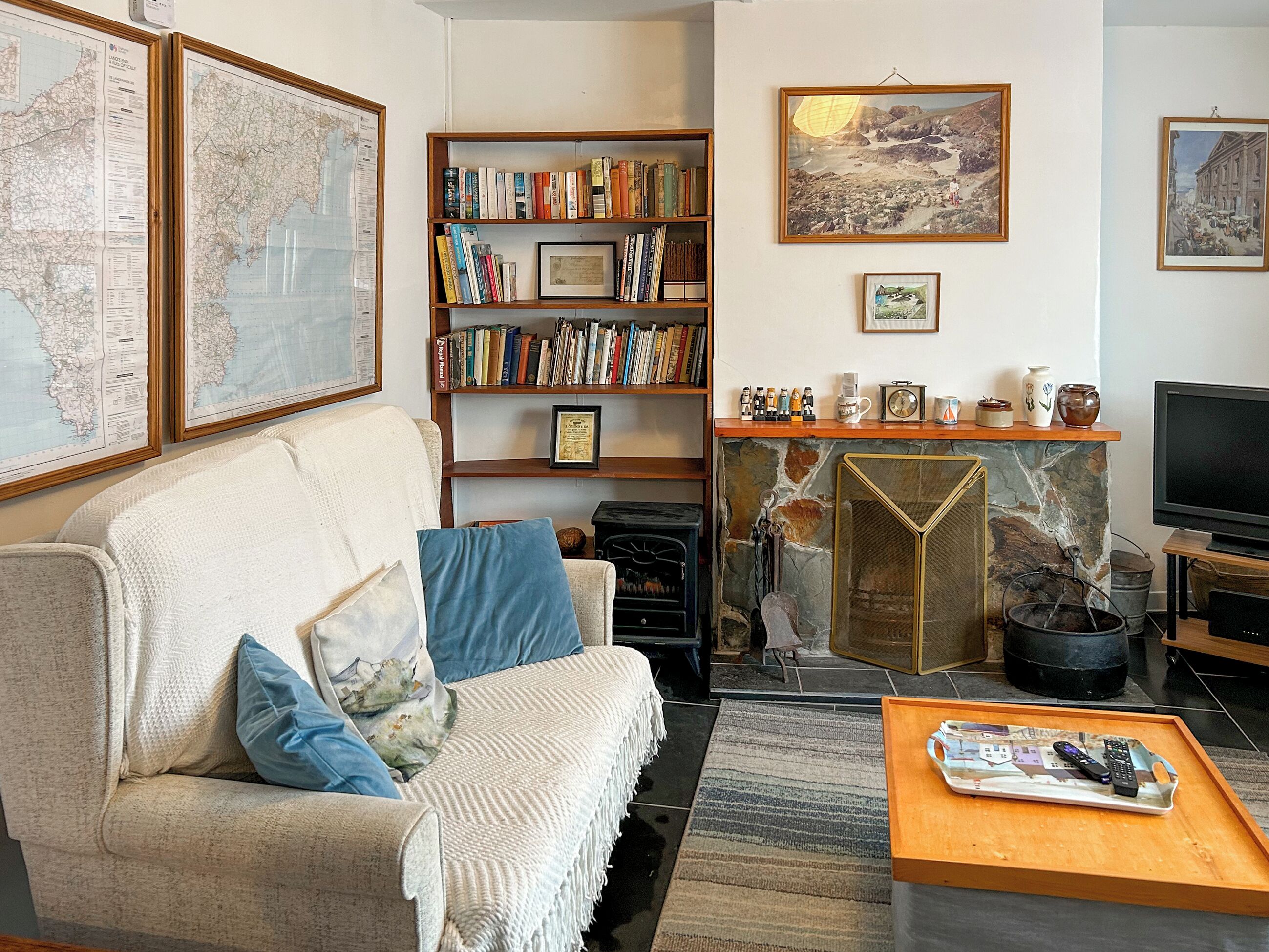 A living room with a sofa, bookshelf, fireplace, and a television.