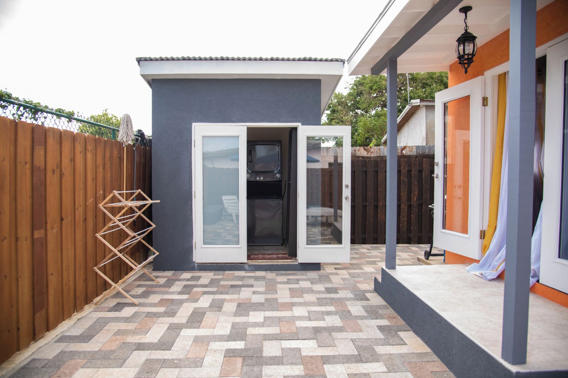 A patio area with a tiled floor, a wooden fence, and a sliding glass door leading to a covered outdoor space.