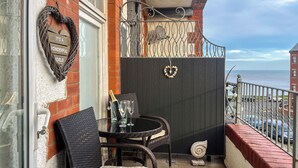 A balcony with wicker chairs, a table with a bottle and glasses, a heart-shaped sign, and a view of the sea. - 1 bedroom accommodation in Whitby (Whitby)