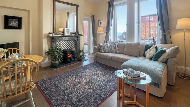 A living room with a fireplace, sofa, and a chandelier. - 1 bedroom accommodation in Whitby (Whitby)