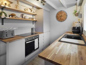 A modern kitchen with a built-in oven, a stovetop, a sink, and wooden countertops. - 1 bedroom accommodation in Guisborough (Guisborough)
