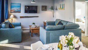 Un salon avec deux canapés, une table basse et un coin repas avec une table dressée pour deux personnes.