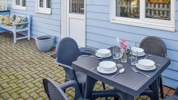 Une terrasse avec une table dressée pour le repas, des si èges d’extérieur et le numéro de la maison, qui est le 22.