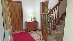 A hallway with wooden doors, a red rug, a lamp, a small cabinet, and a wooden staircase. - 3 bedroom accommodation in Areley Kings, Near Stourport on Severn (Areley Kings, Near Stourport on Severn)