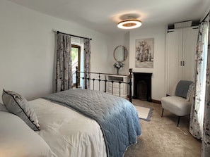 Une chambre à coucher comprenant un lit, un bureau, une chaise, une cheminée et une armoire.