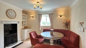 A dining area with a round table, red upholstered chairs, a fireplace, and wall-mounted lighting. - 3 bedroom accommodation in Areley Kings, Near Stourport on Severn (Areley Kings, Near Stourport on Severn)