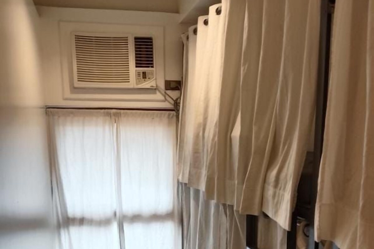 A room with a window, a bench, and a bunk bed with curtains.