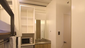 A compact kitchen with a microwave, refrigerator, and wooden cabinets. - Quarto PH (Makati)