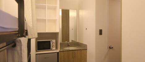 Una cocina compacta con microondas, refrigerador y armarios de madera.
