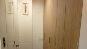 A narrow hallway with wooden doors and a thermostat on the wall. - Quarto PH (Makati)