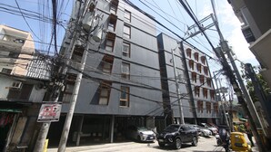 A multi-story building with a loading area sign, parked cars, and a tuk-tuk on the street. - Quarto PH (Makati)