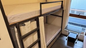 A bunk bed with a desk and chair, curtains, and a window. - Quarto PH (Makati)