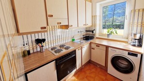 Une cuisine compacte avec des meubles de rangement en bois, une cuisinière, un lave-vaisselle et un lave-linge.