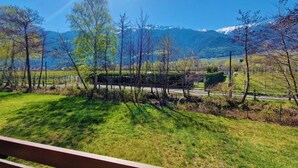 Une vue panoramique d’un paysage montagneux, avec une route et des arbres au premier plan.