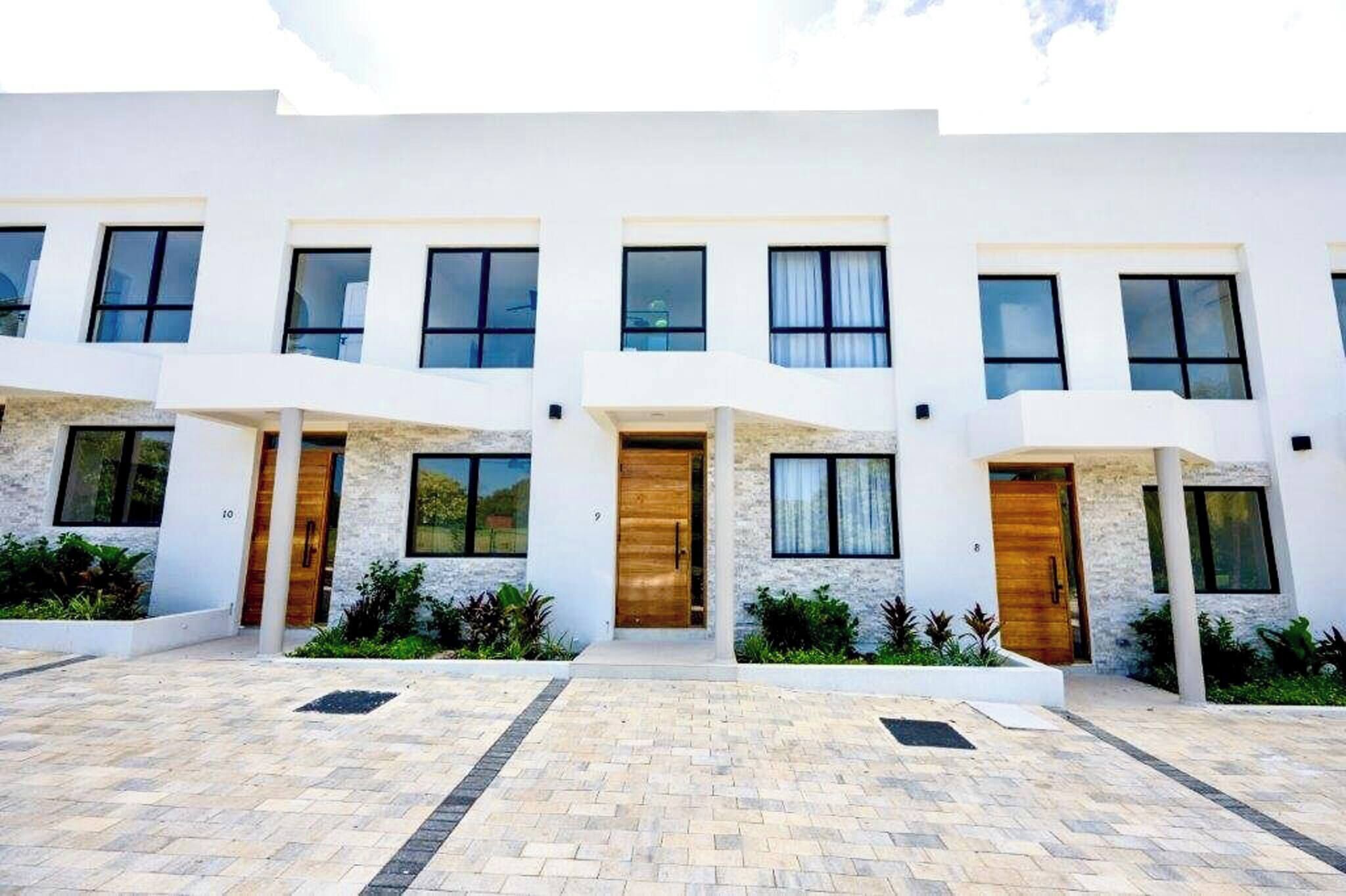 A modern multi-story building with a symmetrical facade, large windows, and a central entrance with a wooden door.