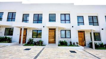 A modern multi-story building with a symmetrical facade, large windows, and a central entrance with a wooden door.