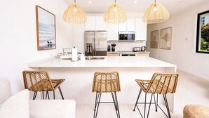 A modern kitchen with a large island, wicker chairs, and pendant lighting. - Azzurro Townhouses - by Zenbreak (Speightstown)