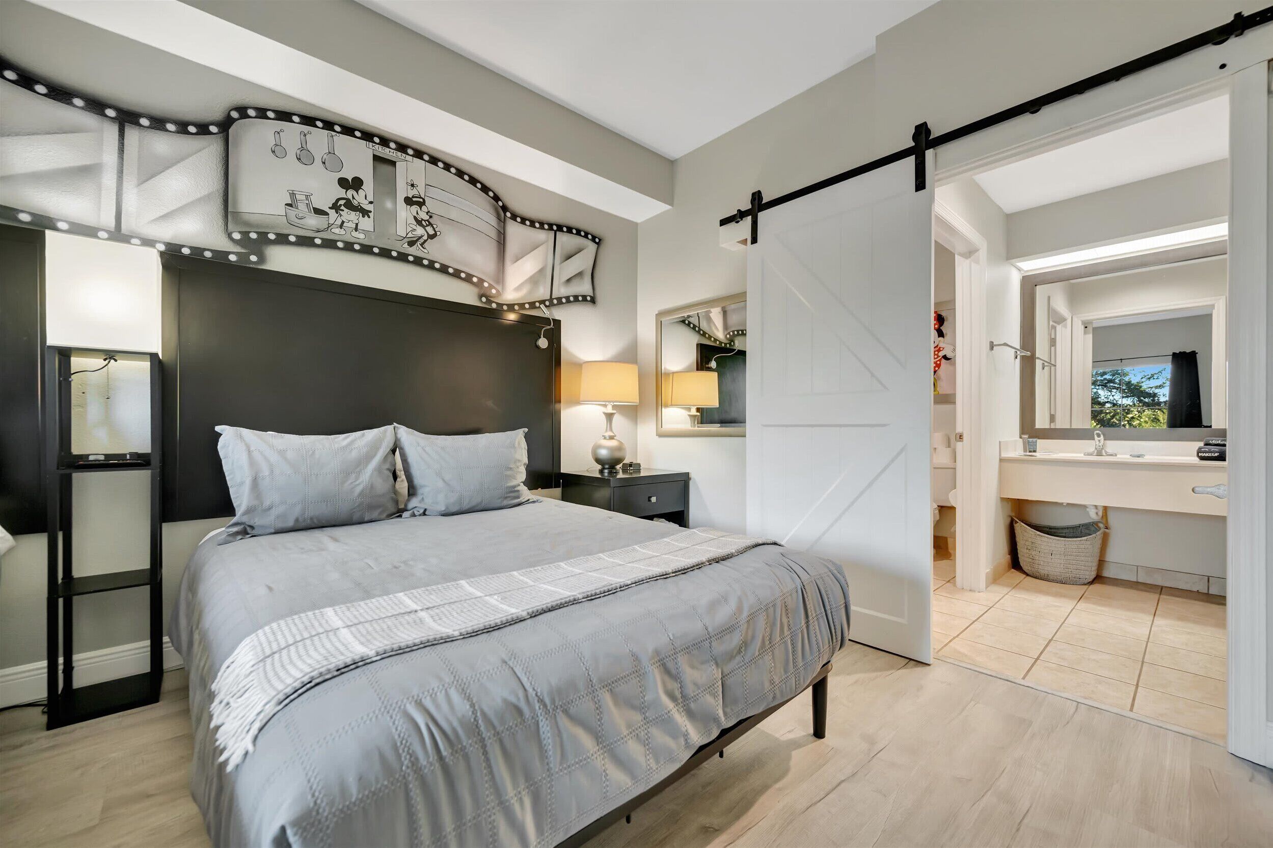 Ein Schlafzimmer mit einem großen Bett, Nachttischen, einem Spiegel und einer Schiebetür zu einem Badezimmer.