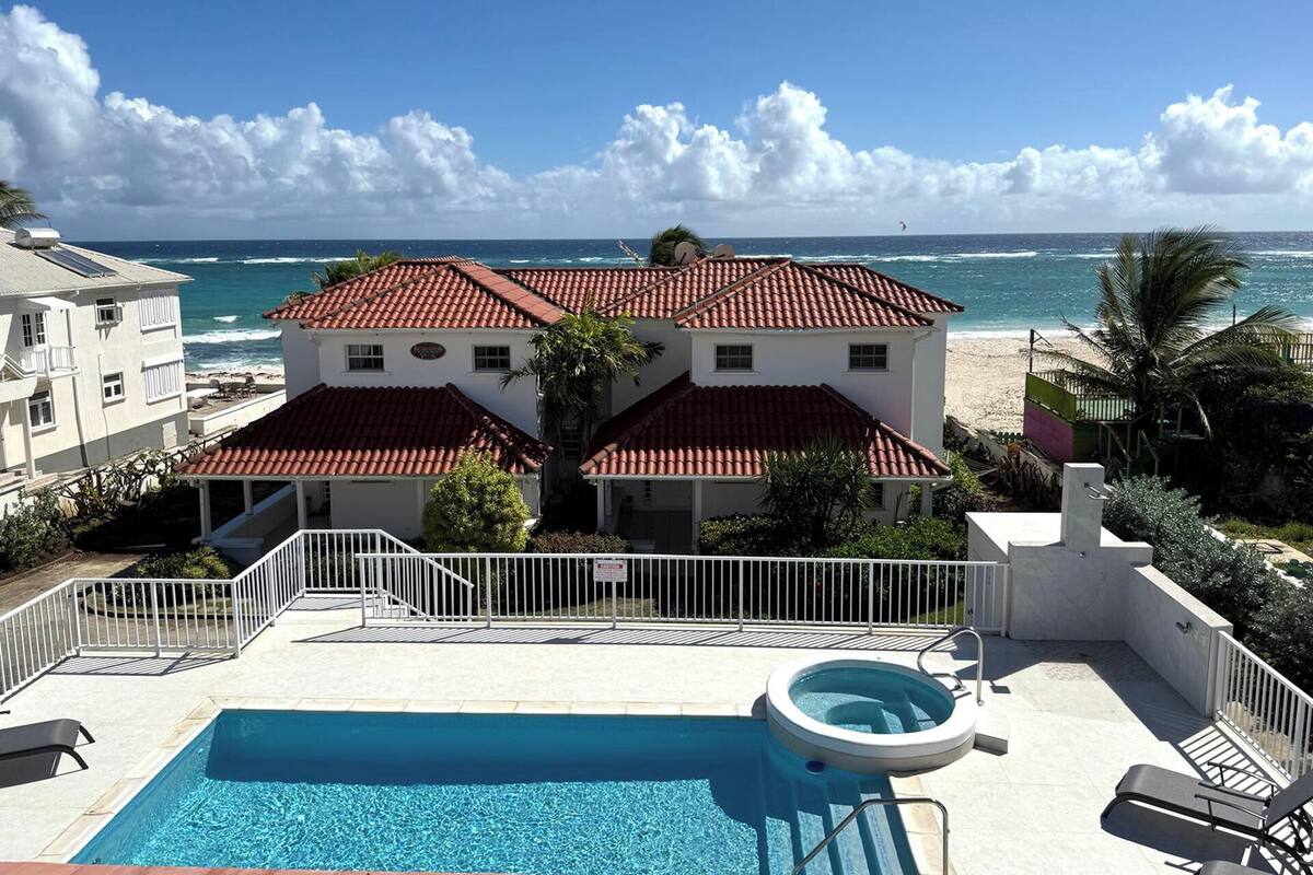 Ein zweistöckiges Gebäude mit rotem Ziegeldach, einem Schwimmbad und Blick auf den Ozean.