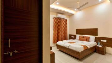 A bedroom with a wooden bed, a ceiling fan, and an air conditioning unit.