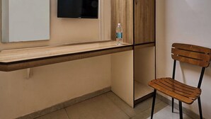 Una stanza piccola e luminosa con una toeletta in legno, uno specchio, una televisione e una sedia di legno.