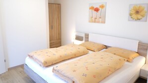 A double bed with floral-patterned bedding, a wooden wardrobe, and two wall-mounted flower paintings. - Apartment Weitblick - Alpstay (Naturno)