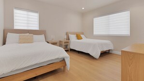 Ein Schlafzimmer mit zwei Betten, Holz-Kopfteilen, Nachttischen und einem Holztisch.