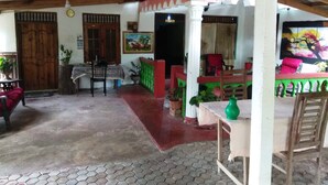 Una habitación con suelo de baldosas, muebles de madera, una mesa con un florero verde y un cuadro en la pared.
