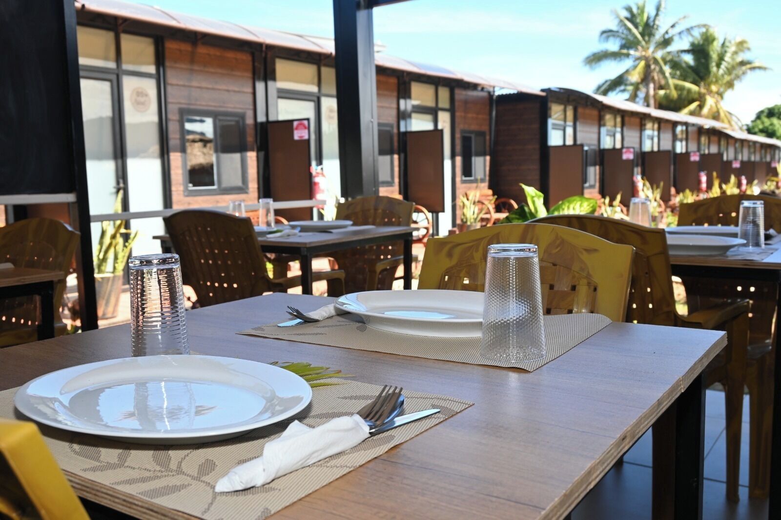 A dining area with tables set for two, equipped with plates, cutlery, and a salt shaker.