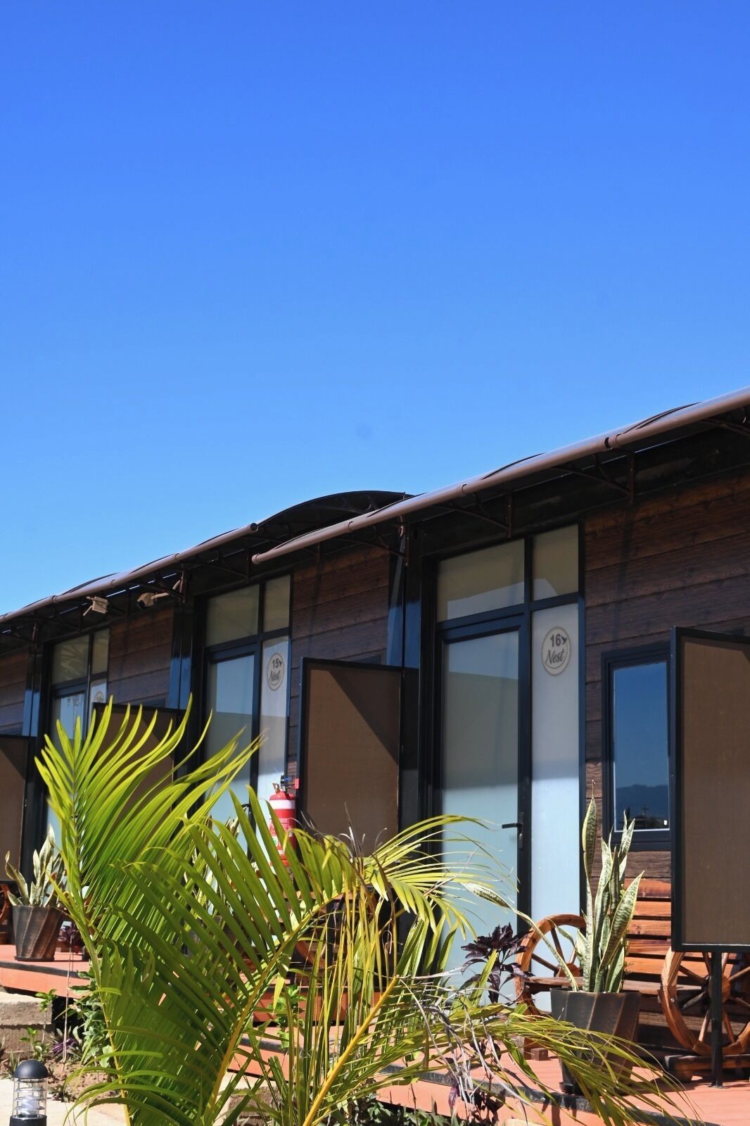 A building with large windows, a wooden facade, and a clear blue sky.