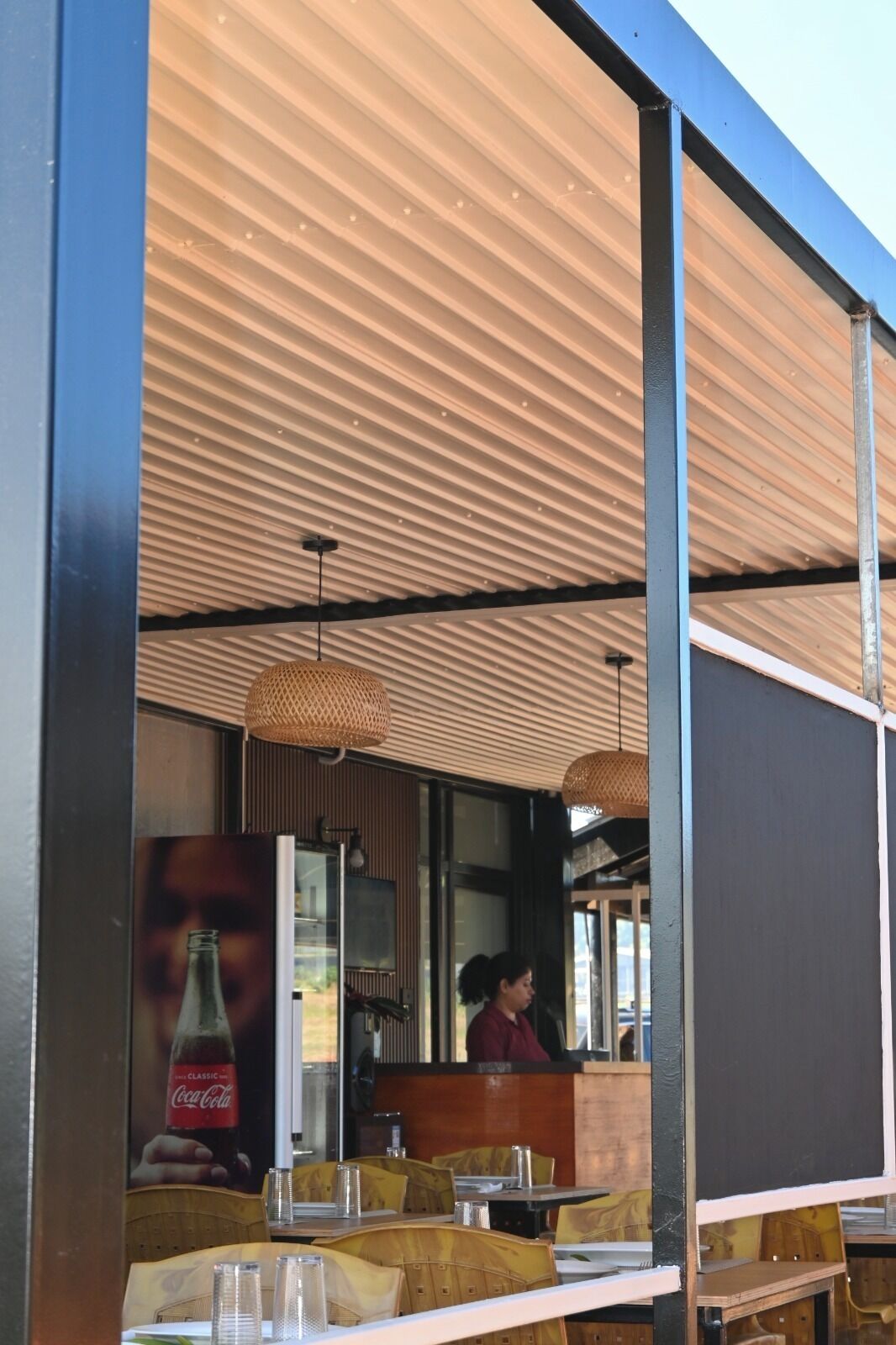 An outdoor dining area with tables and chairs, a counter, and a large poster.