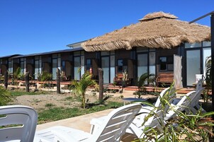 Un resort con construcciones de techo de paja, asientos al aire libre y un cielo despejado.