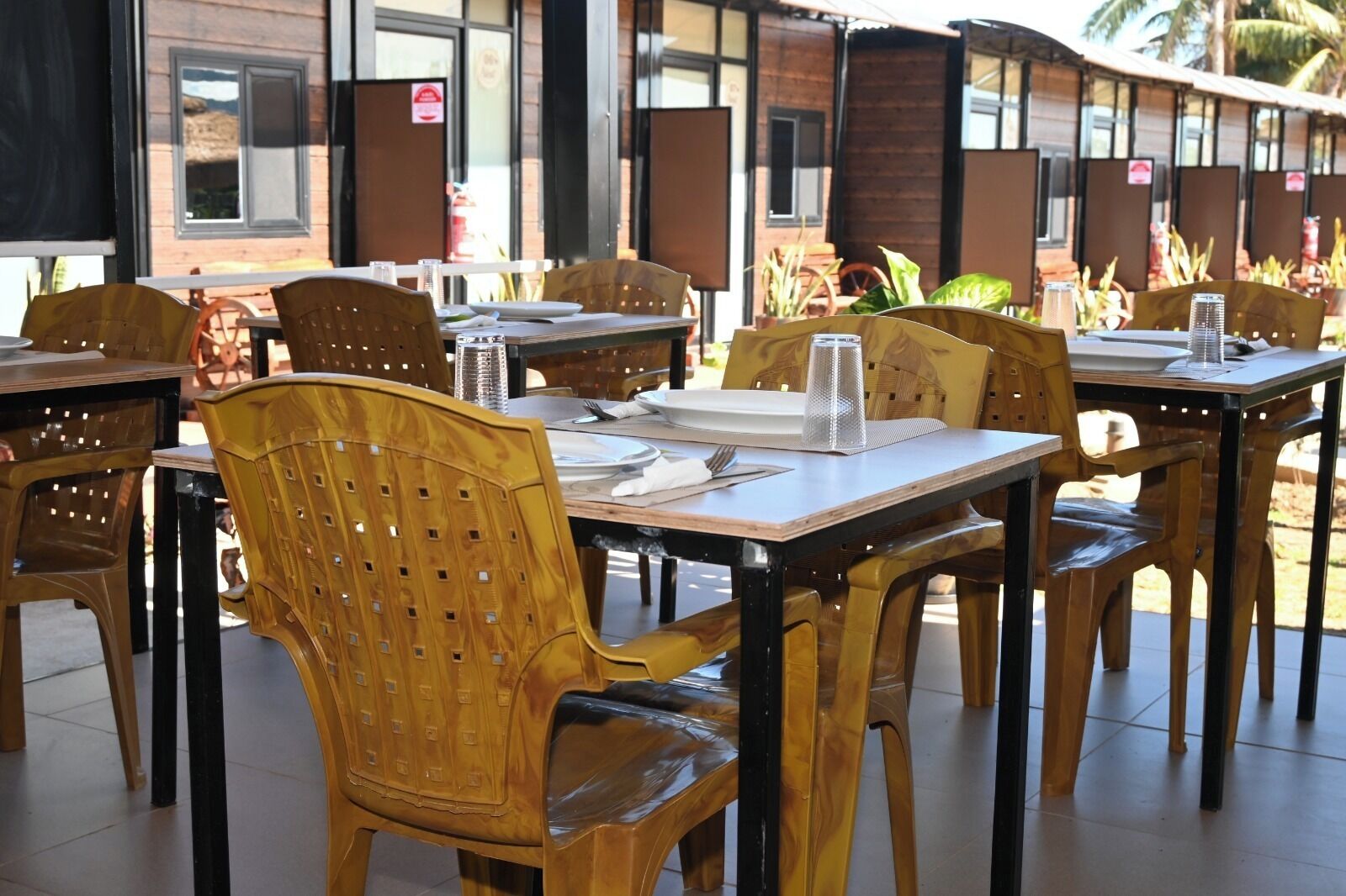 A restaurant with outdoor seating, wooden chairs, and tables.