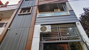 A multi-story building with a modern architectural design, featuring balconies, large windows, and an air conditioning unit on the exterior wall. - Hotel Shiv Sagar  (Varanasi)