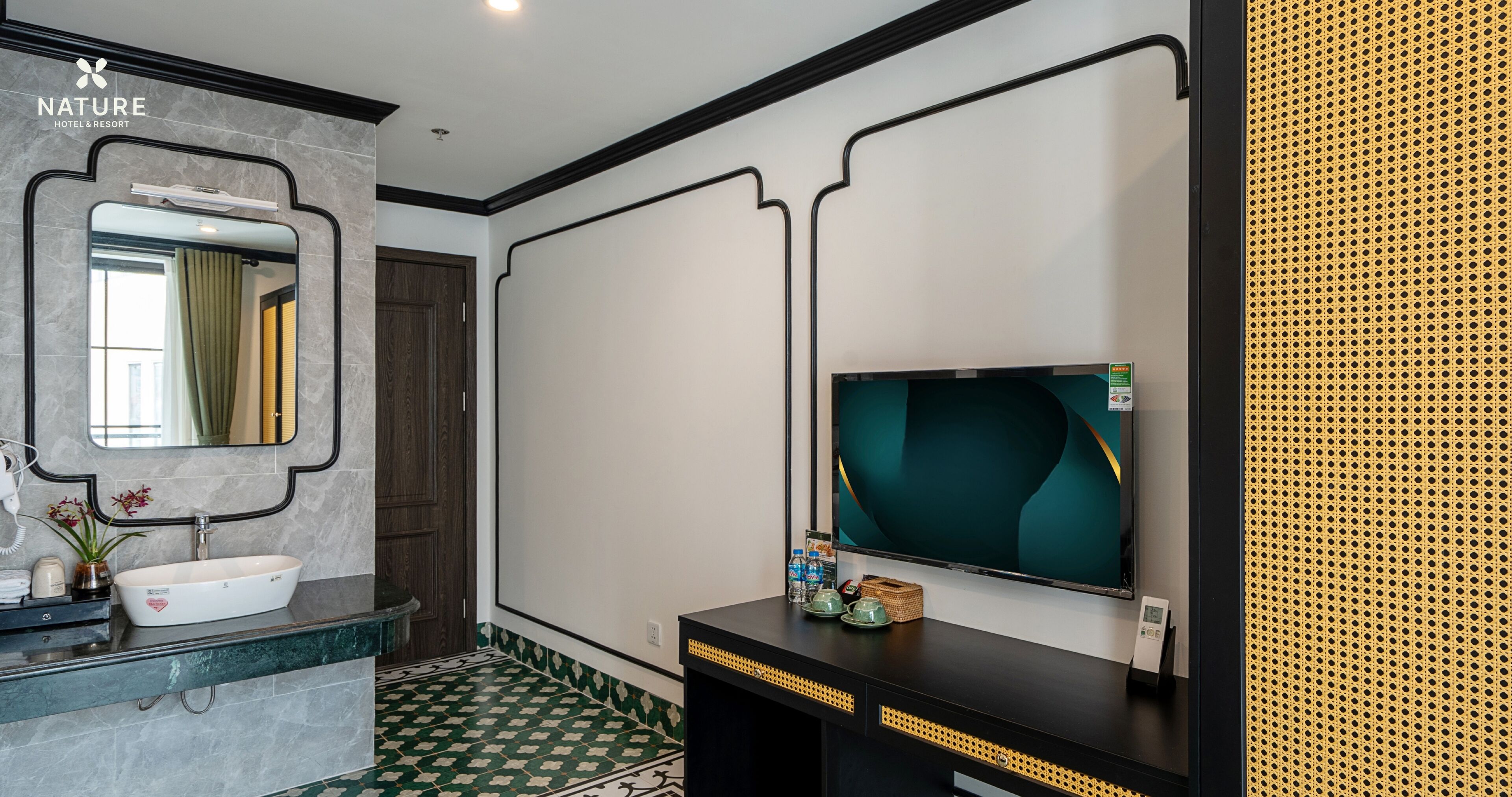 A modern bathroom with a white sink, a mirror, a flat-screen TV, and a patterned floor.