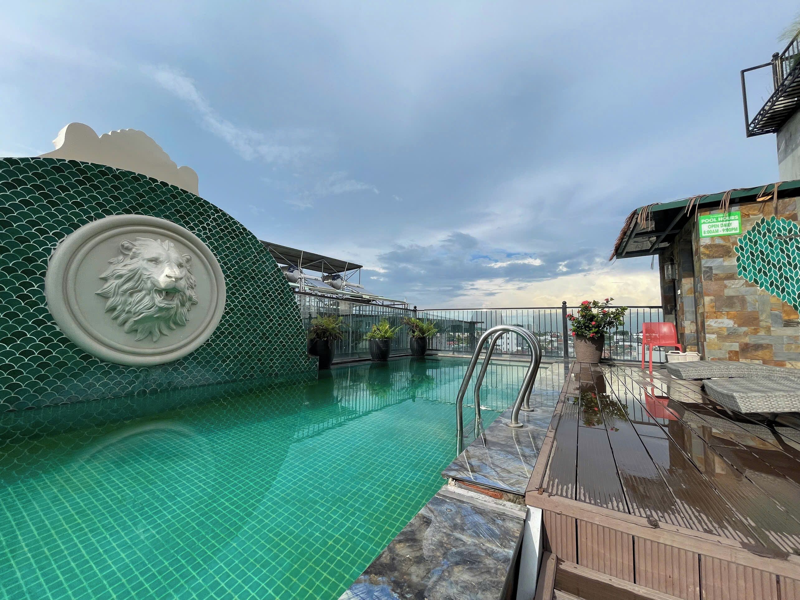 Ein Pool auf dem Dach mit einer Skulptur eines Löwenkopfes, einer Glasbrüstung und einem Schild mit den Poolöffnungszeiten.