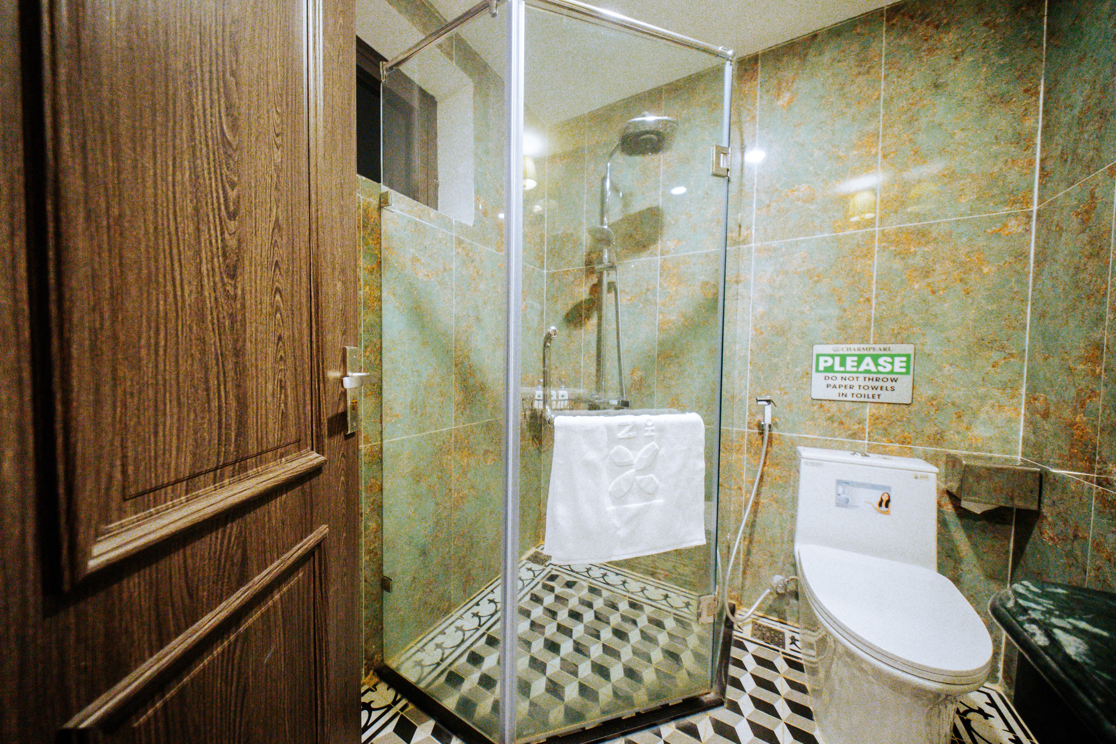A bathroom with a glass-enclosed shower, a toilet, and a sink.