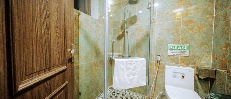 A bathroom with a glass-enclosed shower, a toilet, and a sink.