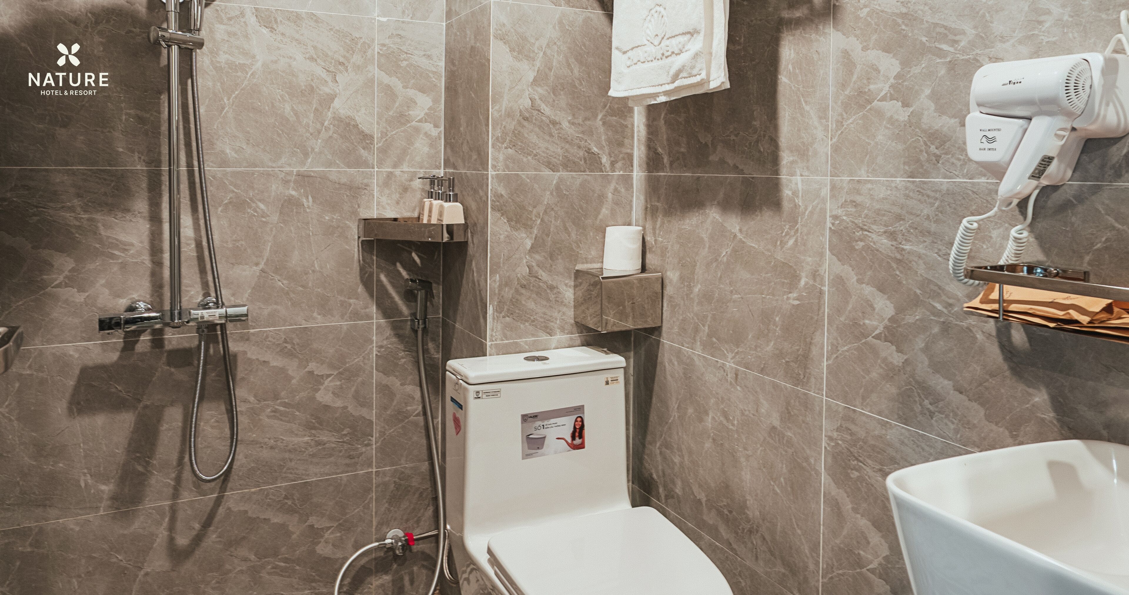 A modern bathroom with a shower, toilet, and hairdryer.