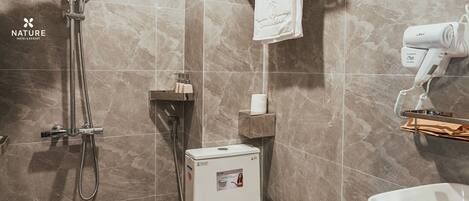 A modern bathroom with a shower, toilet, and hairdryer.