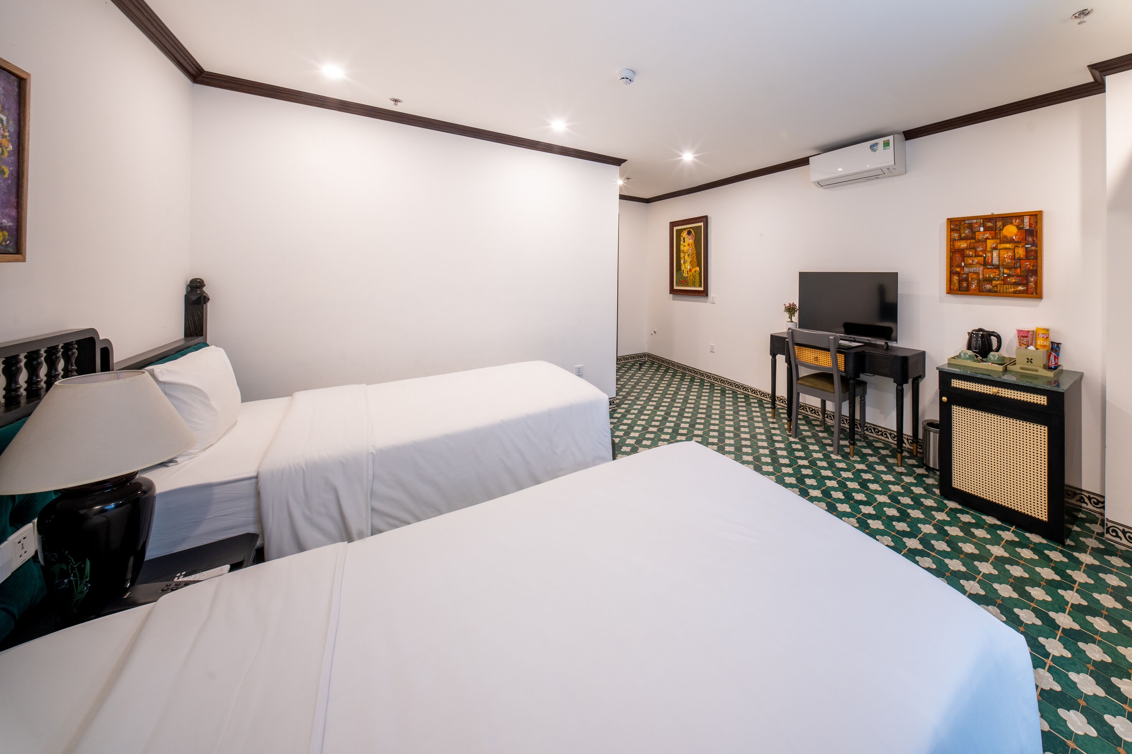 A hotel room with two beds, a desk, a television, and a coffee maker.